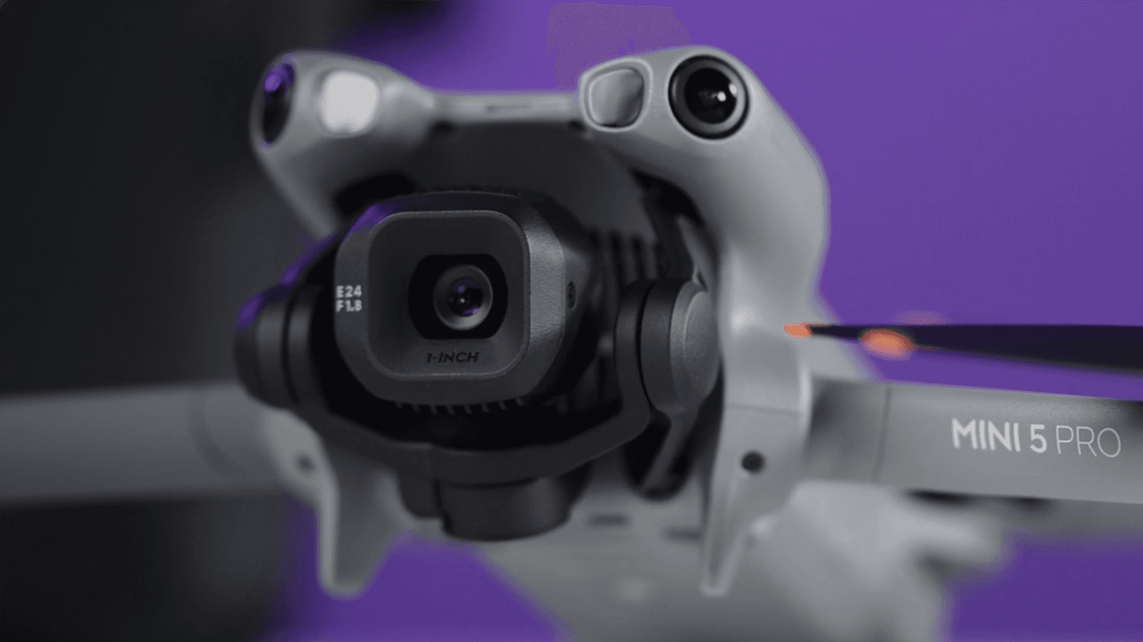 En närbild av en avancerad drönarkamera med texten 'MINI 5 PRO' synlig på armen, mot en lila bakgrund.
