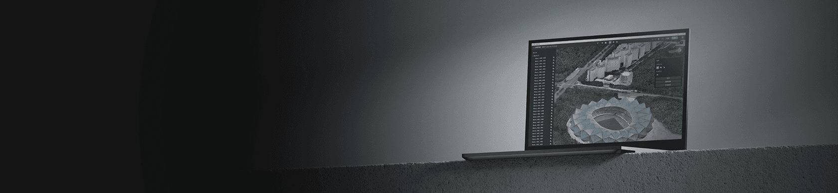 En bärbar dator visar en detaljerad satellitbild av ett stadion och omgivande stadsområde, placerad mot en mörk bakgrund.