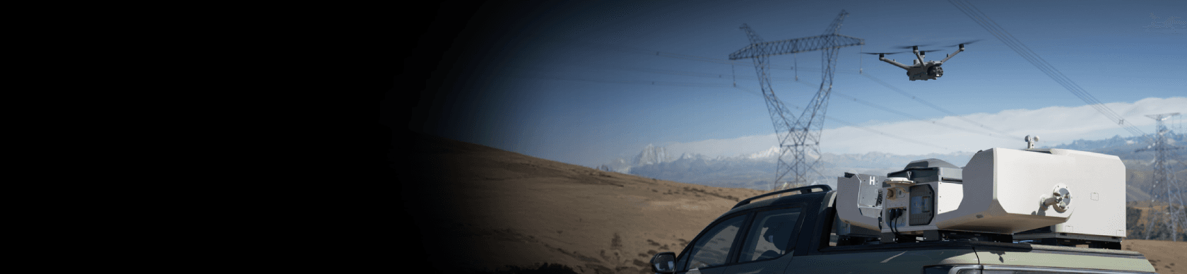 En drönare flyger nära kraftledningar i ett bergigt landskap, medan en avancerad utrustning är monterad på ett fordon i förgrunden.