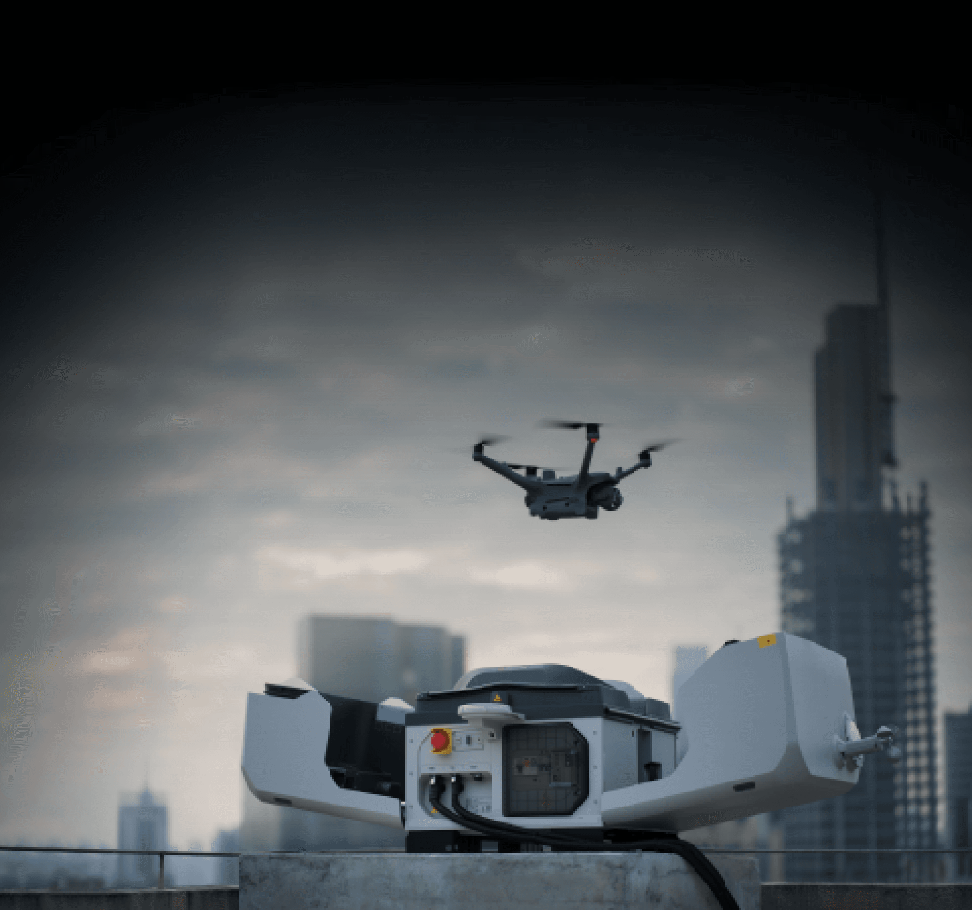 En drönare lyfter från en laddningsstation på ett tak med en stadssilhuett i bakgrunden.