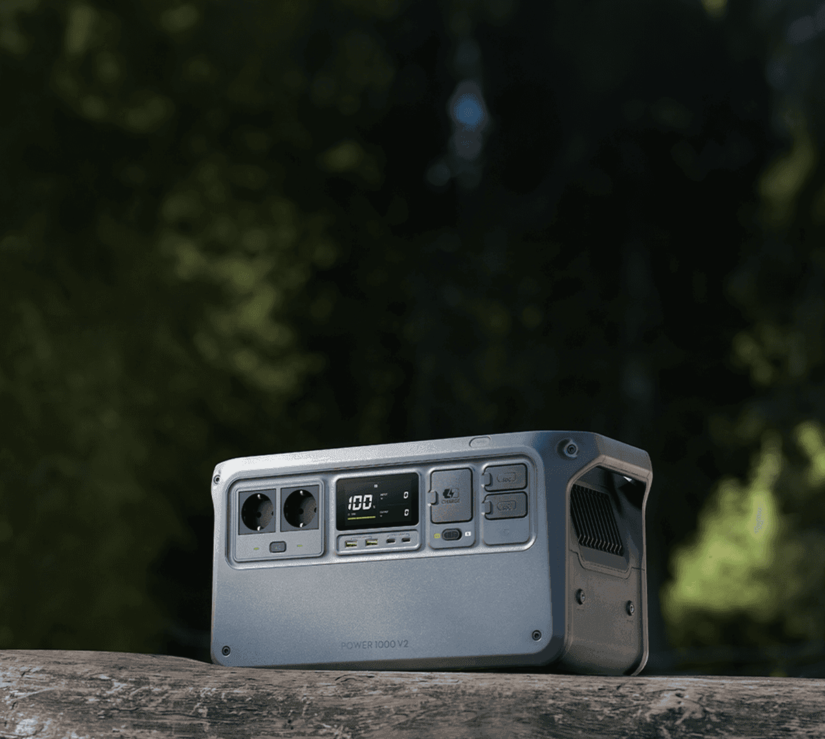 En bärbar kraftstation placerad på en trädstam i en skogsmiljö, redo att leverera energi utomhus.