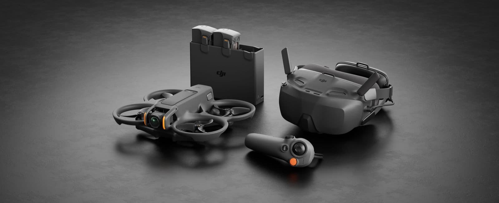 En avancerad drönare med tillhörande VR-headset, fjärrkontroll och batteriladdare visas på en stilren, mörk yta.