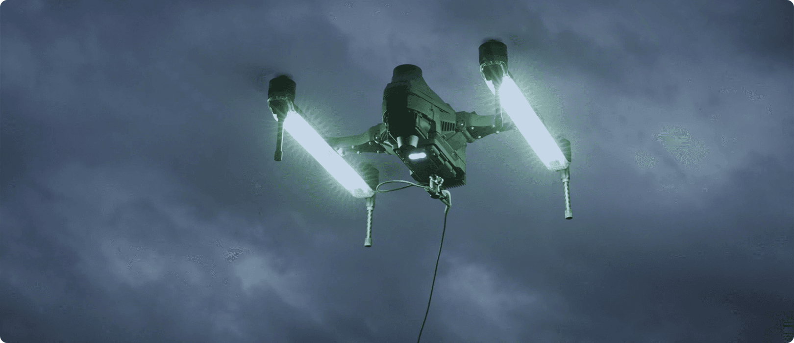 En belysningsdrönare (CZI CZ100) med starka lysrör flyger genom en mörk och molnig himmel.