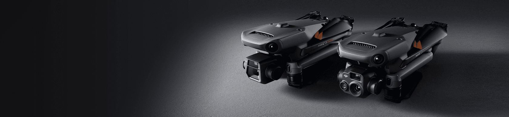Två avancerade drönare ligger sida vid sida på en mörk yta, med fokus på deras sofistikerade kamerautrustning.