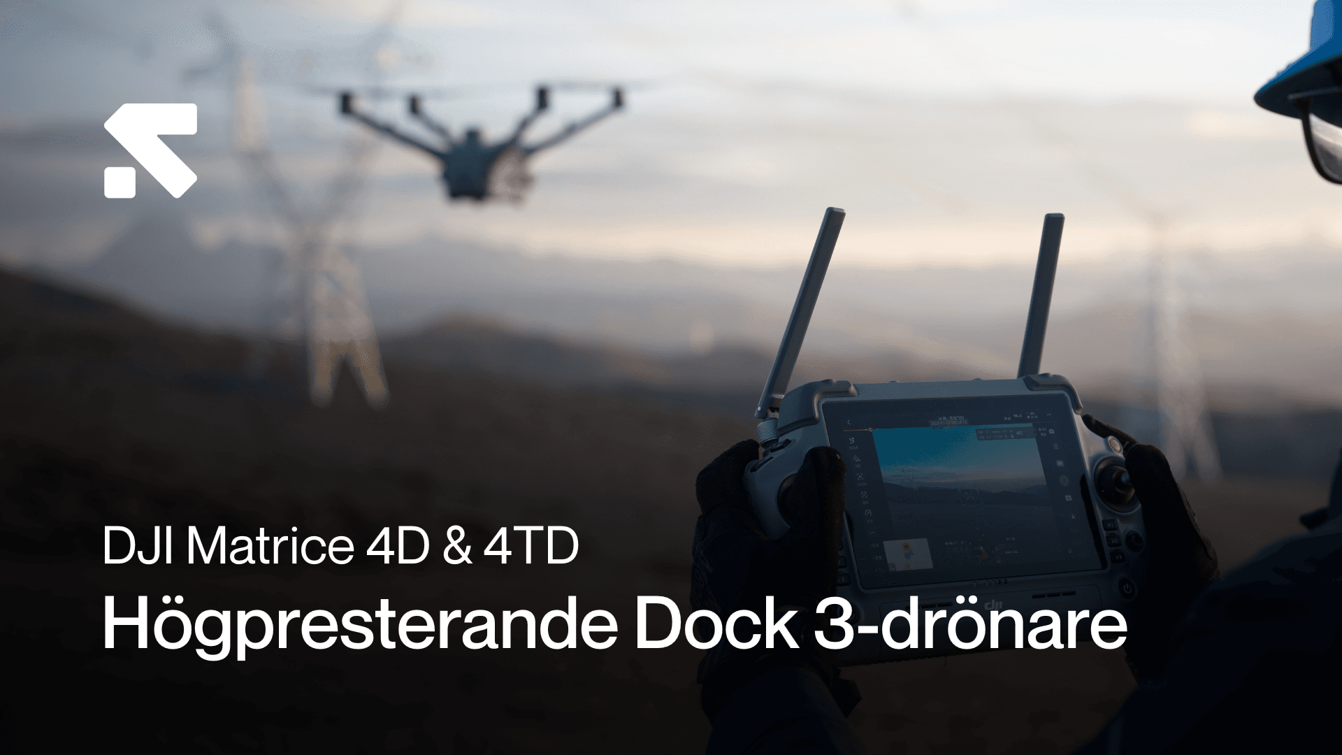 En person styr en drönare med en fjärrkontroll i en öppen landskapsmiljö, med kraftledningar i bakgrunden.