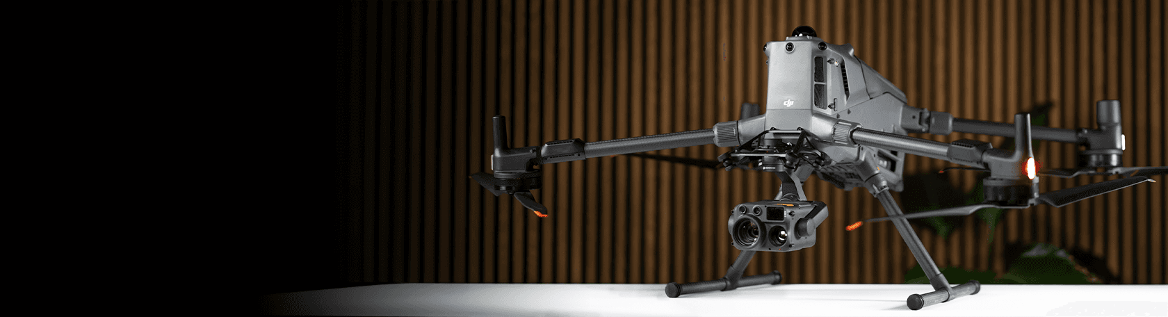 En avancerad Matrice 400-drönare med flera sensorer står på ett bord i en modern inomhusmiljö med träpaneler i bakgrunden.
