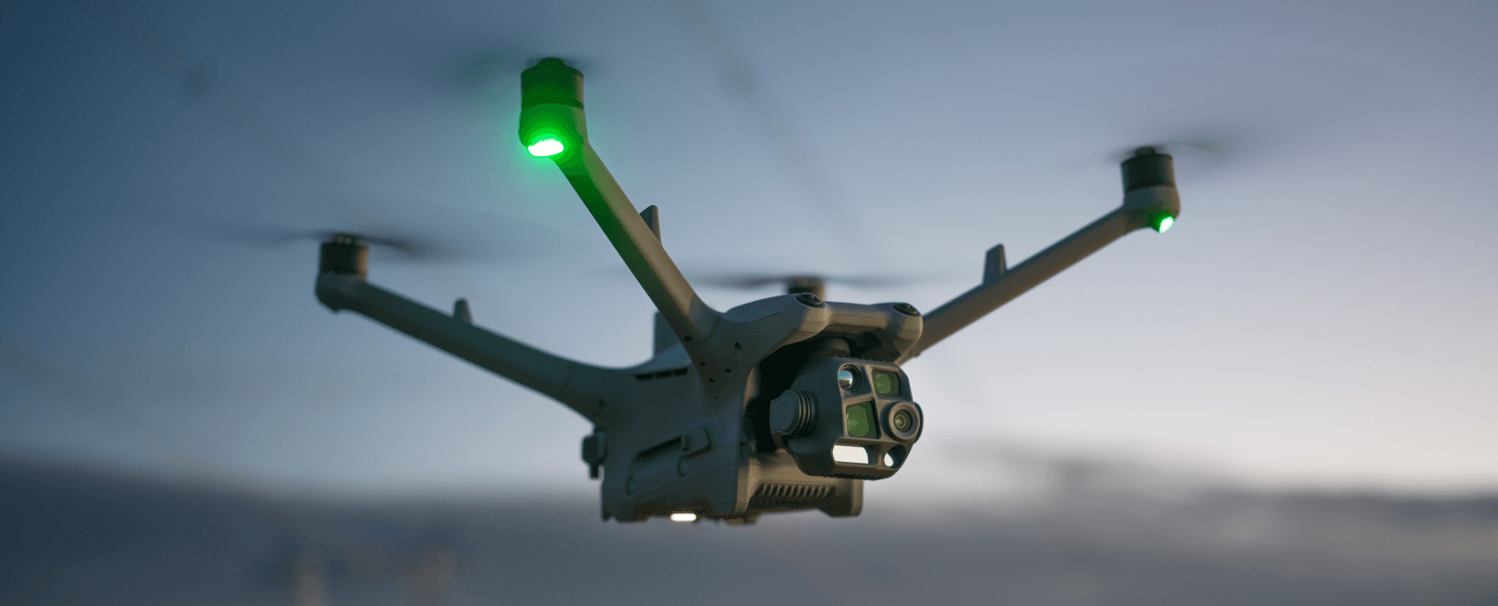 Bilden visar en flygande DJI Matrice 4TD-drönare i skymning med grön belysning