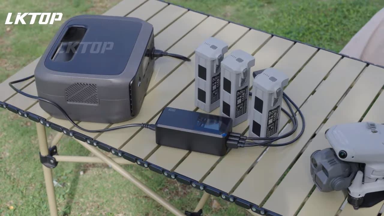 En bärbar kraftstation laddar flera drönarbatterier på ett hopfällbart bord utomhus.