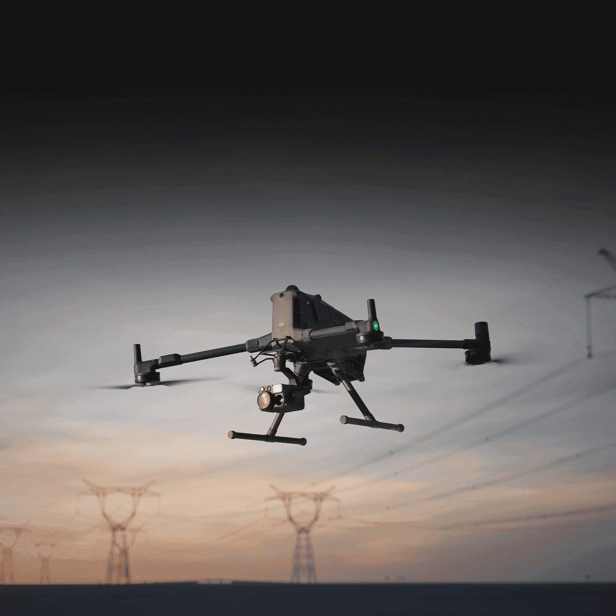 En drönare svävar i skymningen nära kraftledningar, redo för inspektionsarbete.