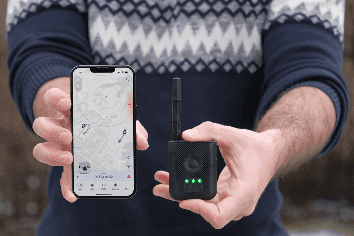 En person håller en smartphone med en kartapp och en kompakt svart enhet med antenn och lysdioder, vilket antyder användning av GPS-teknik.