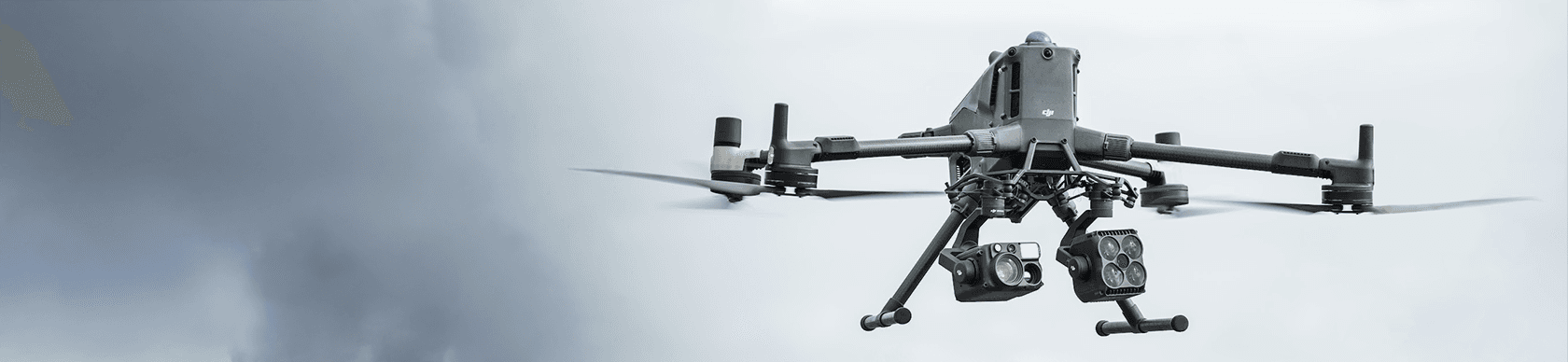 En avancerad drönare svävar i luften mot en molnig himmel, utrustad med flera sensorer och kameror.