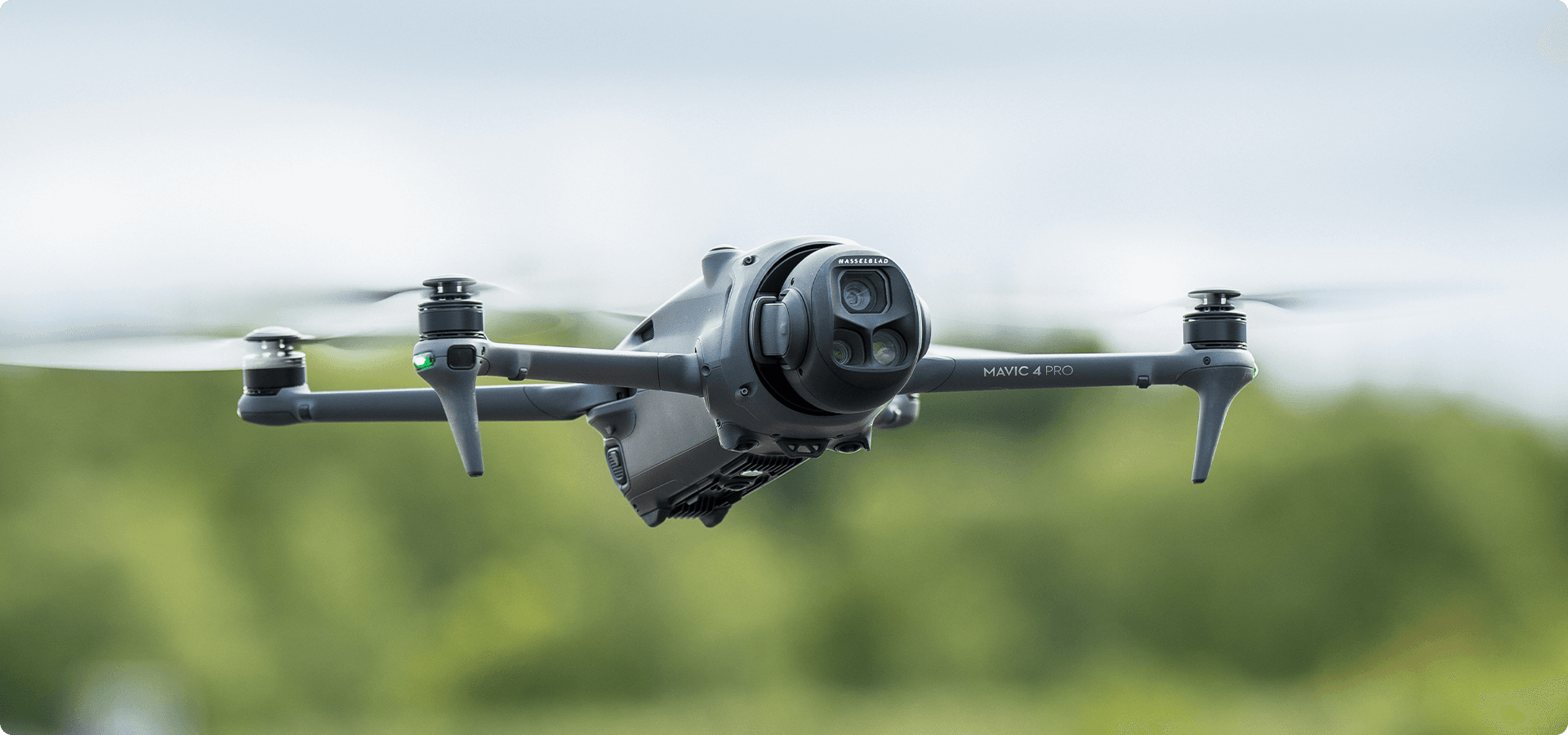 En drönare av modellen Mavic 4 Pro svävar i luften mot en suddig grön bakgrund.