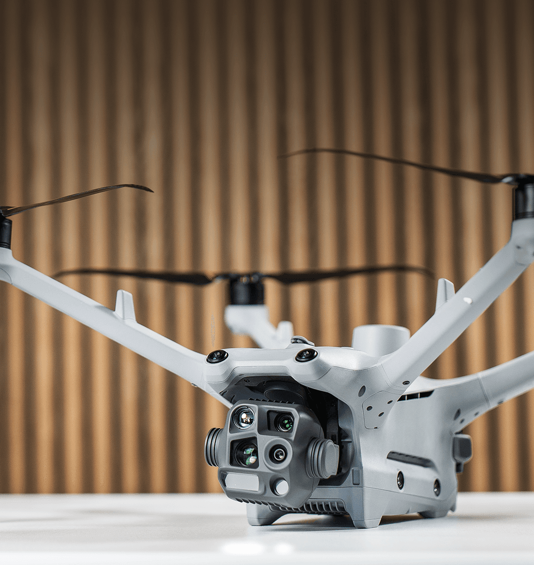 En avancerad DJI Matrice 4TD-drönare med flera kameror och sensorer visas mot en träpanelbakgrund.