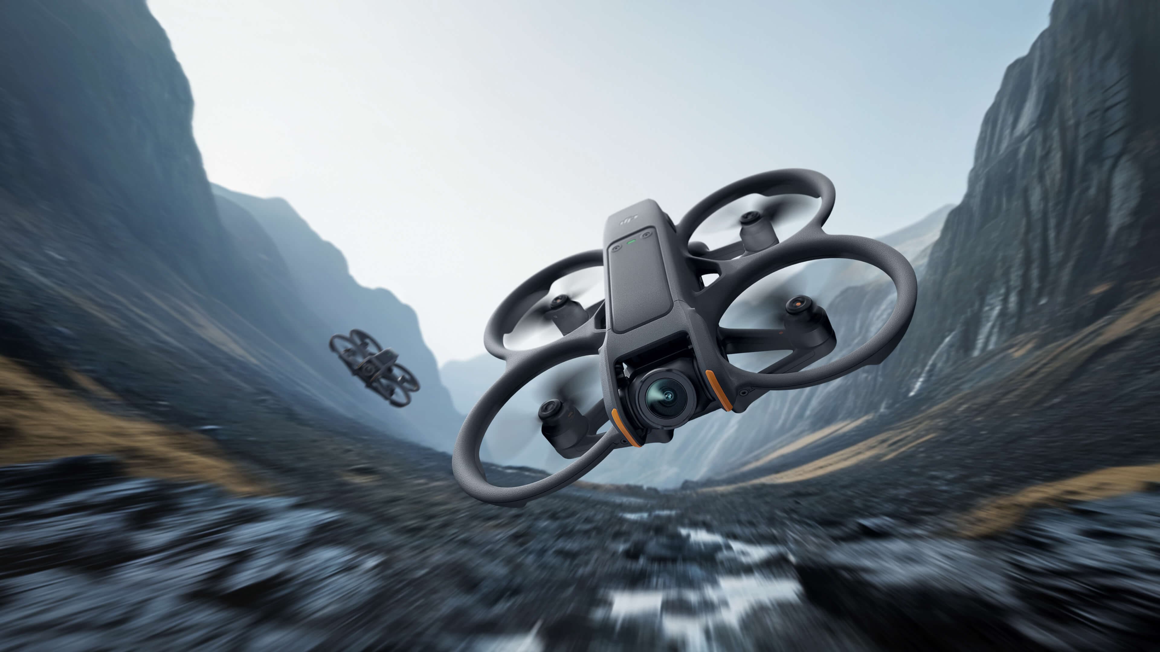 Två DJI Avata 2 flyger lågt genom en dimmig bergsdal med klippväggar på båda sidor