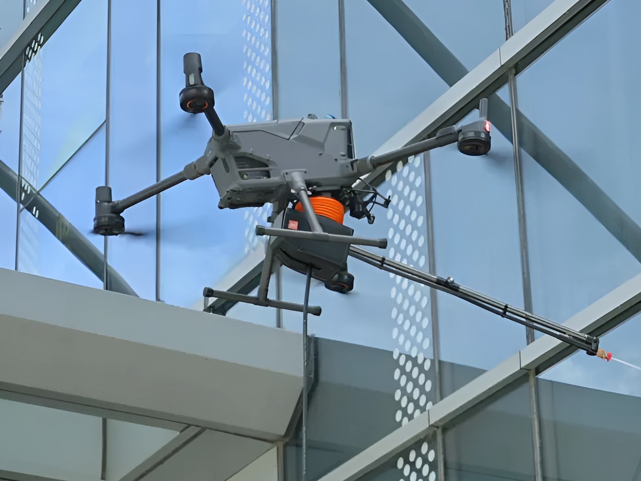 Drönaren DJI Matrice 400 tvättar ett fönster på ett höghus med tvättsystemet Wisson Orion AP3-P3
